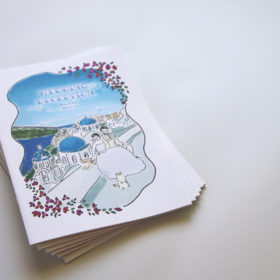 サントリーニ島の景色と新郎新婦のイラストが描かれた冊子の表紙